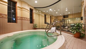 A spa area with a large indoor pool, exercise equipment, and potted plants.