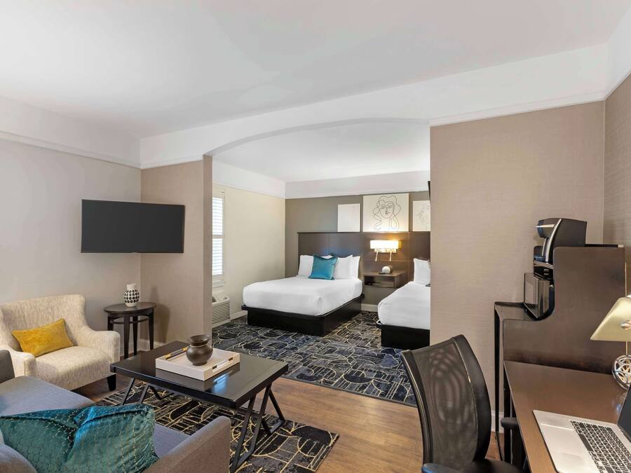 Una habitación de hotel con cama, sofá, escritorio, televisor y lámpara.