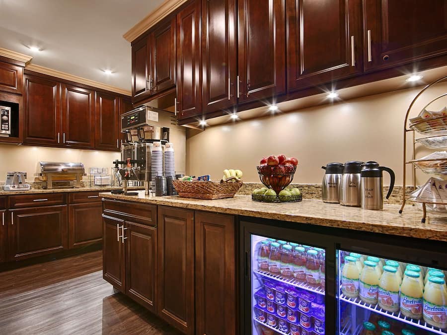 Una cucina moderna con mobili in legno scuro, elettrodomestici in acciaio inossidabile e un frigorifero integrato pieno di bevande.