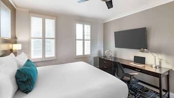 A hotel room with a bed, desk, chair, and ceiling fan.