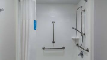 A bathroom with a shower, grab bars, and a bathtub.
