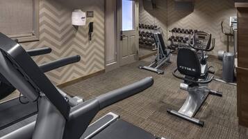 Una palestra alberghiera con tapis roulant, ellittiche e un porta pesi.