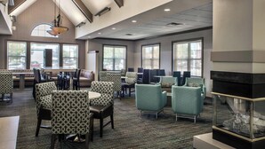 A hotel lobby with patterned chairs, a fireplace, and large windows. - Residence Inn Cranberry Township Pittsburgh by Marriott (Warrendale)
