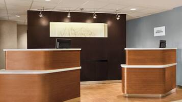 A reception desk with a modern design, a digital screen, and a sign indicating the hotel name.
