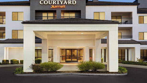 A Courtyard Marriott hotel entrance with a covered walkway, large windows, and a well-lit facade.