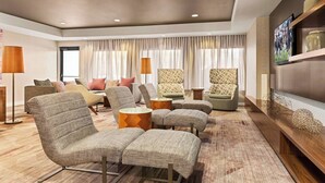 A modern living room with a sofa set, armchairs, a coffee table, and a TV on a wooden shelf.
