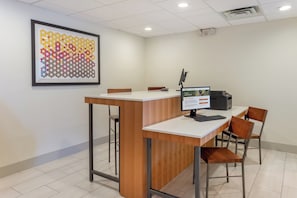 A modern office space with a desk, chairs, a computer, and a framed abstract art piece on the wall.