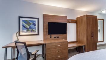 Habitación de hotel con escritorio de madera, televisión, silla, cama y armario.