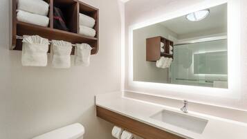 Une salle de bain équipée d’un WC, d’un lavabo, d’un miroir et d’un porte-serviettes avec des serviettes pliées.