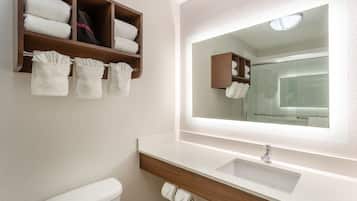 Ein Badezimmer mit Waschbecken, Spiegel, Toilette und Handtuchhalter mit gefalteten Handtüchern.