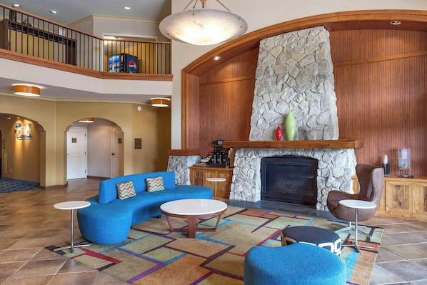 A spacious lobby with a high ceiling, a stone fireplace, a blue sofa, and a coffee table.