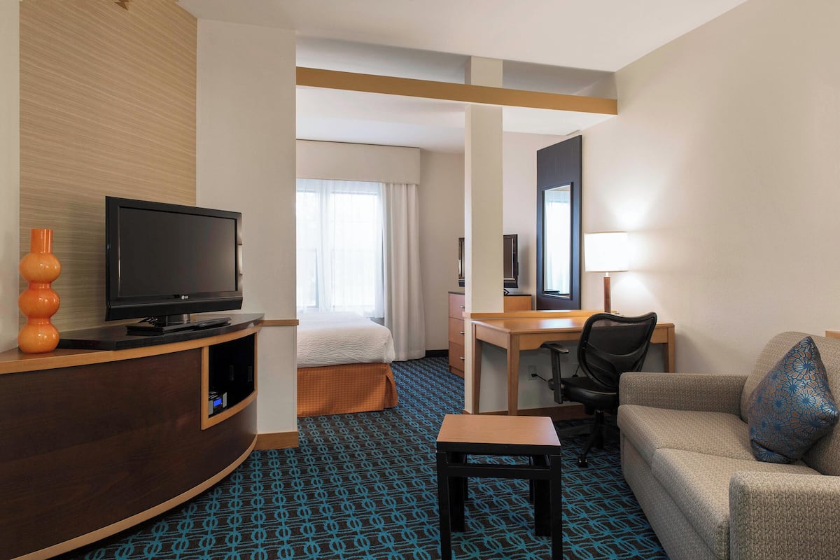 A hotel room with a bed, a desk, a television, a sofa, and a small table.