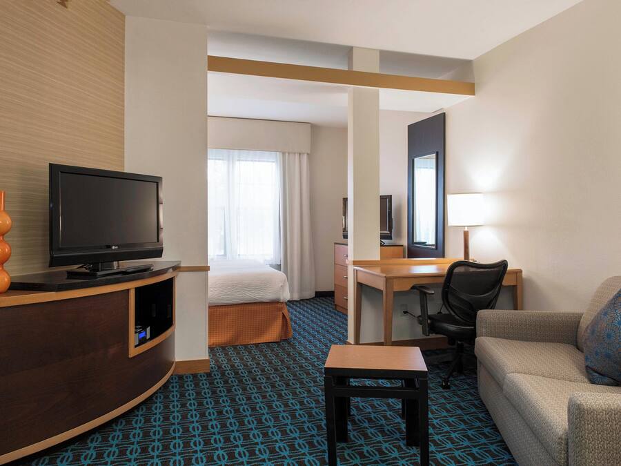 A hotel room with a bed, a desk, a television, a sofa, and a small table.