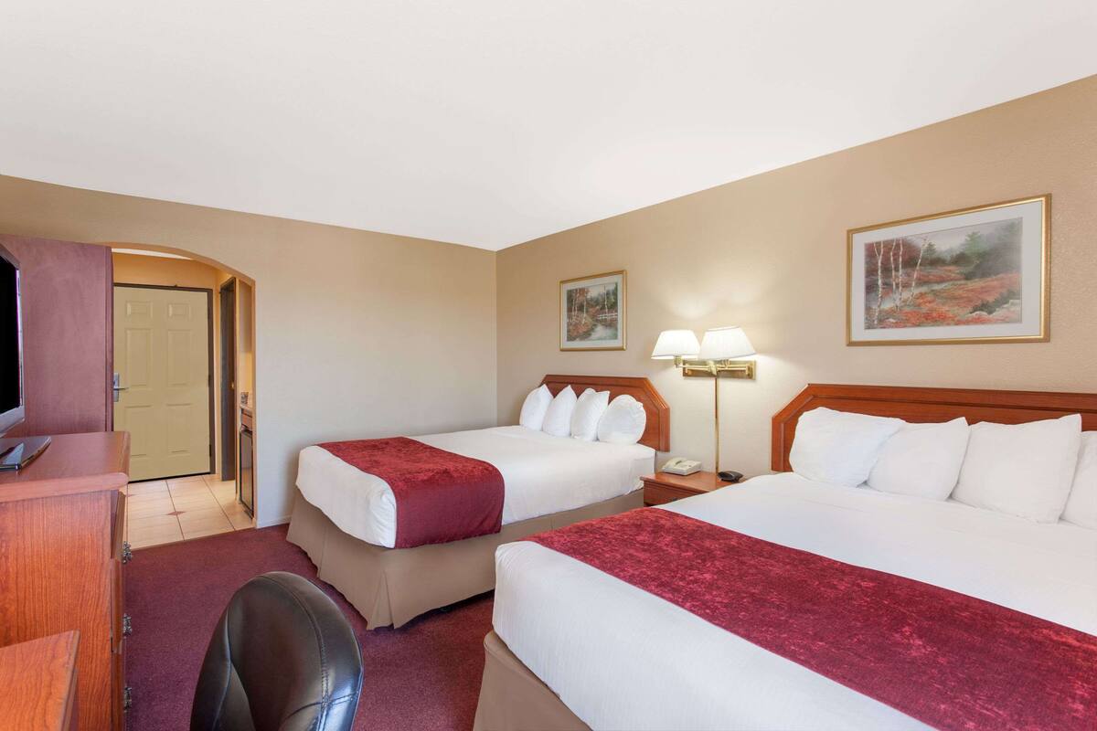 Een hotelkamer met twee bedden, een bureau, een stoel en een televisie.