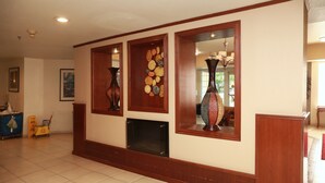 A lobby with a tiled floor, wooden paneling, and a fireplace. - Ramada by Wyndham Fresno Northwest (Fresno)