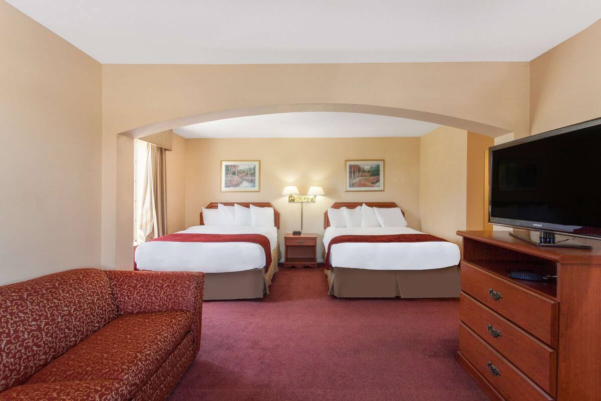 Een hotelkamer met twee bedden, een televisie, een bank en een bureau met lades.