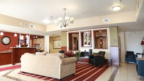 A spacious living area with a beige sofa, a red and white striped rug, and a chandelier. - Ramada by Wyndham Fresno Northwest (Fresno)