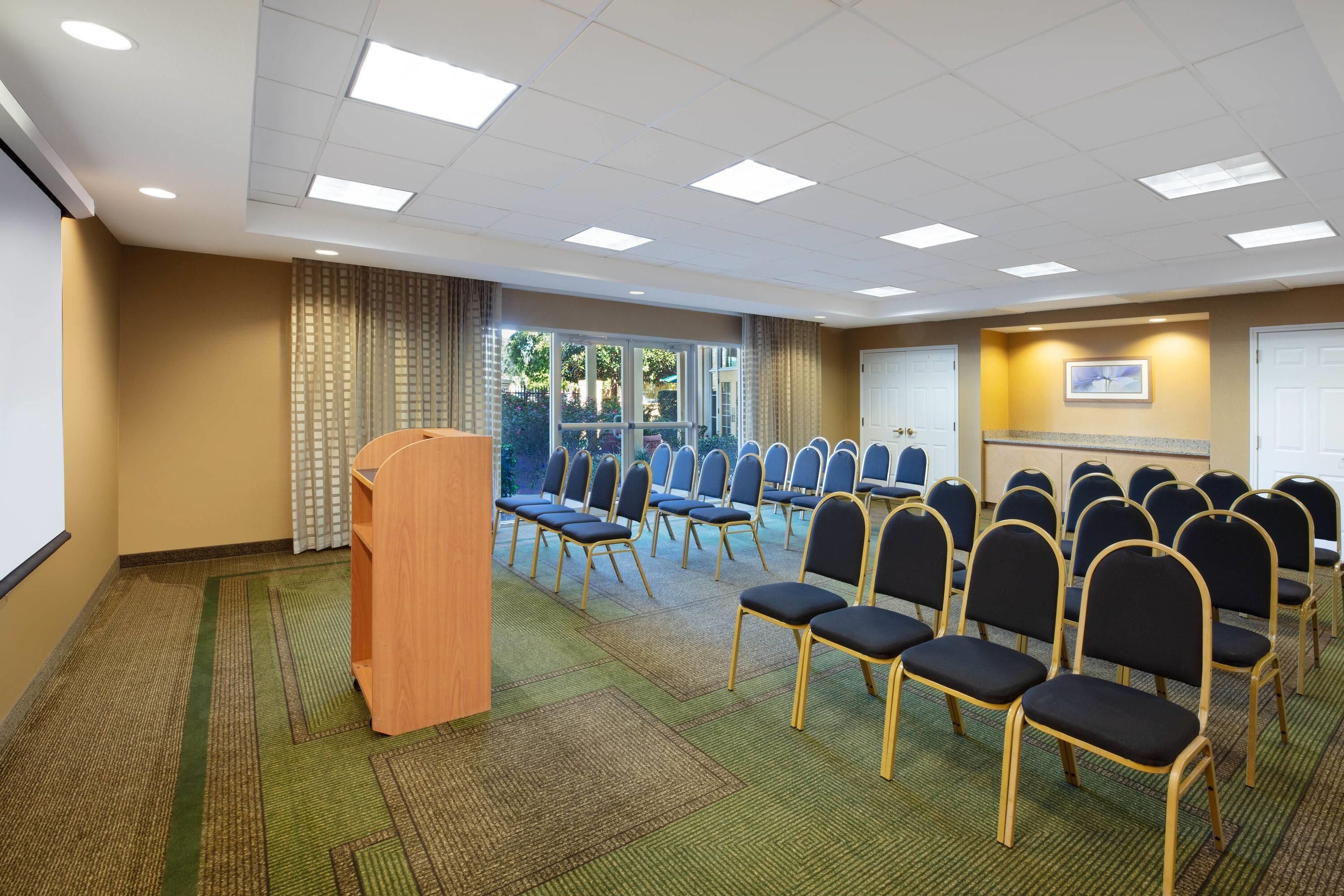 A conference room with rows of chairs, a podium, and a large window.