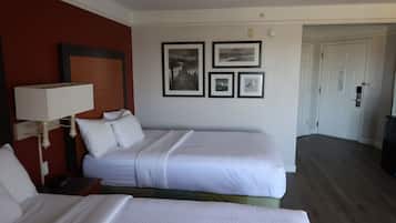 A hotel room with two beds, a nightstand, a lamp, and framed pictures on the wall.
