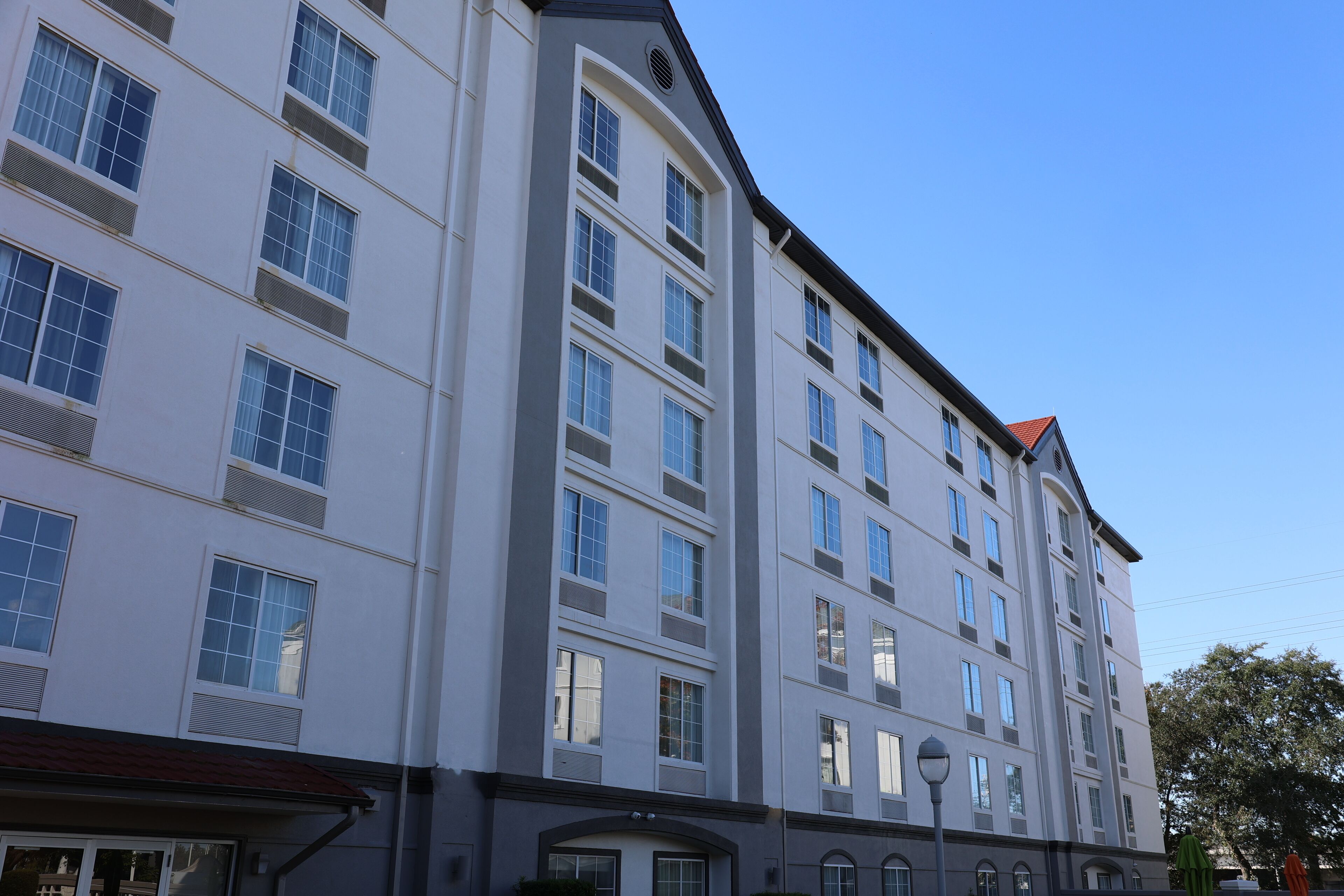 A multi-story hotel with a symmetrical facade, large windows, and a red-tiled roof.