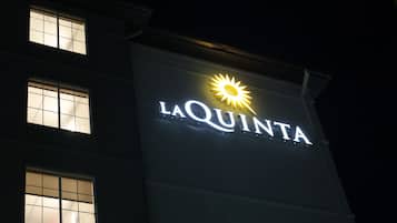 A building with illuminated signage reading "LA QUINTA" and a sun symbol above the text.