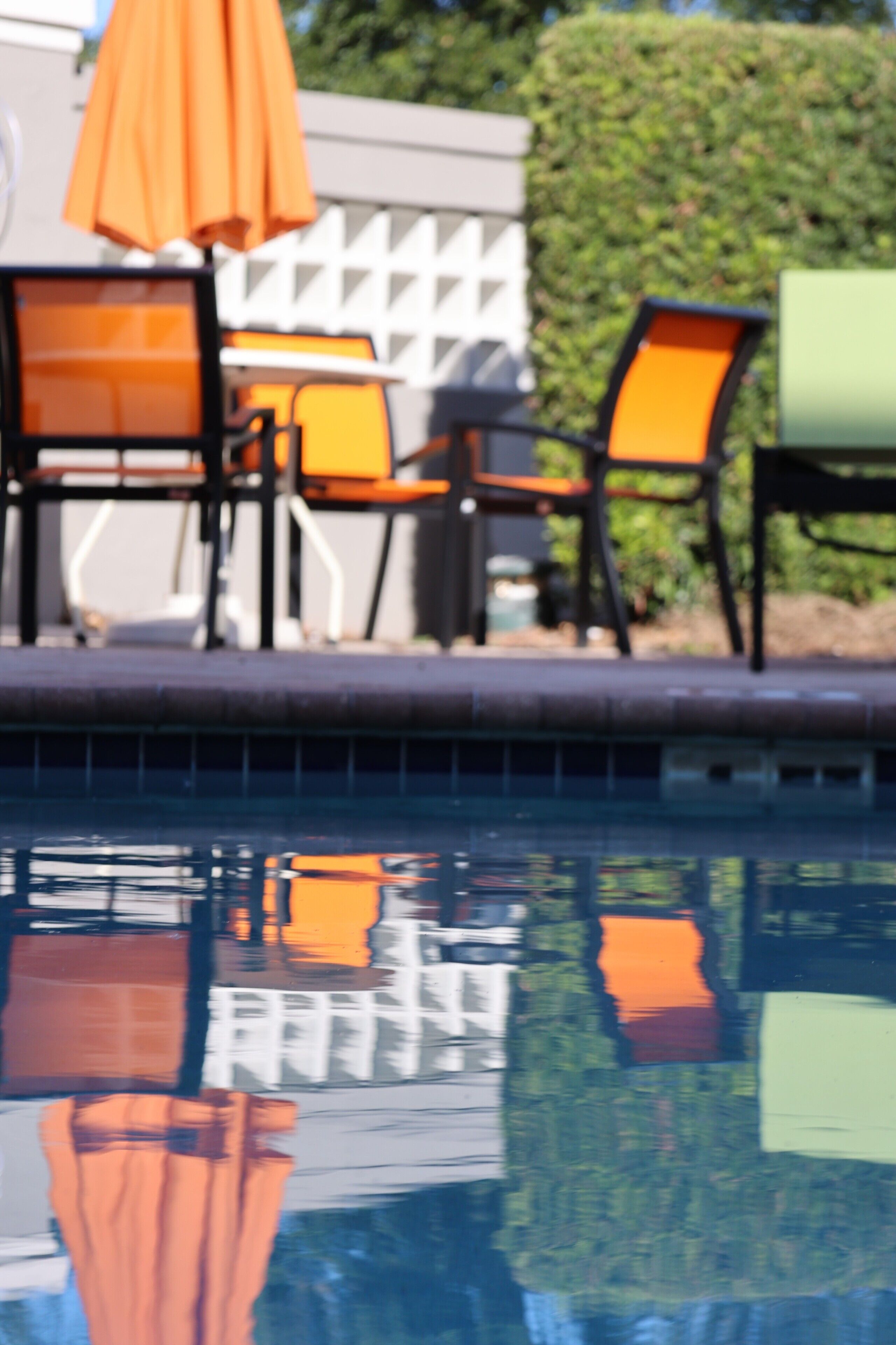 A pool area with chairs and an umbrella.