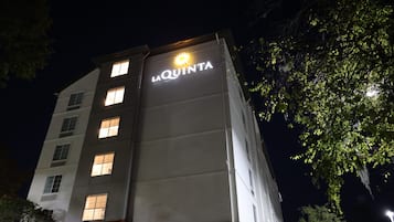 A hotel named La Quinta with illuminated signage at night.