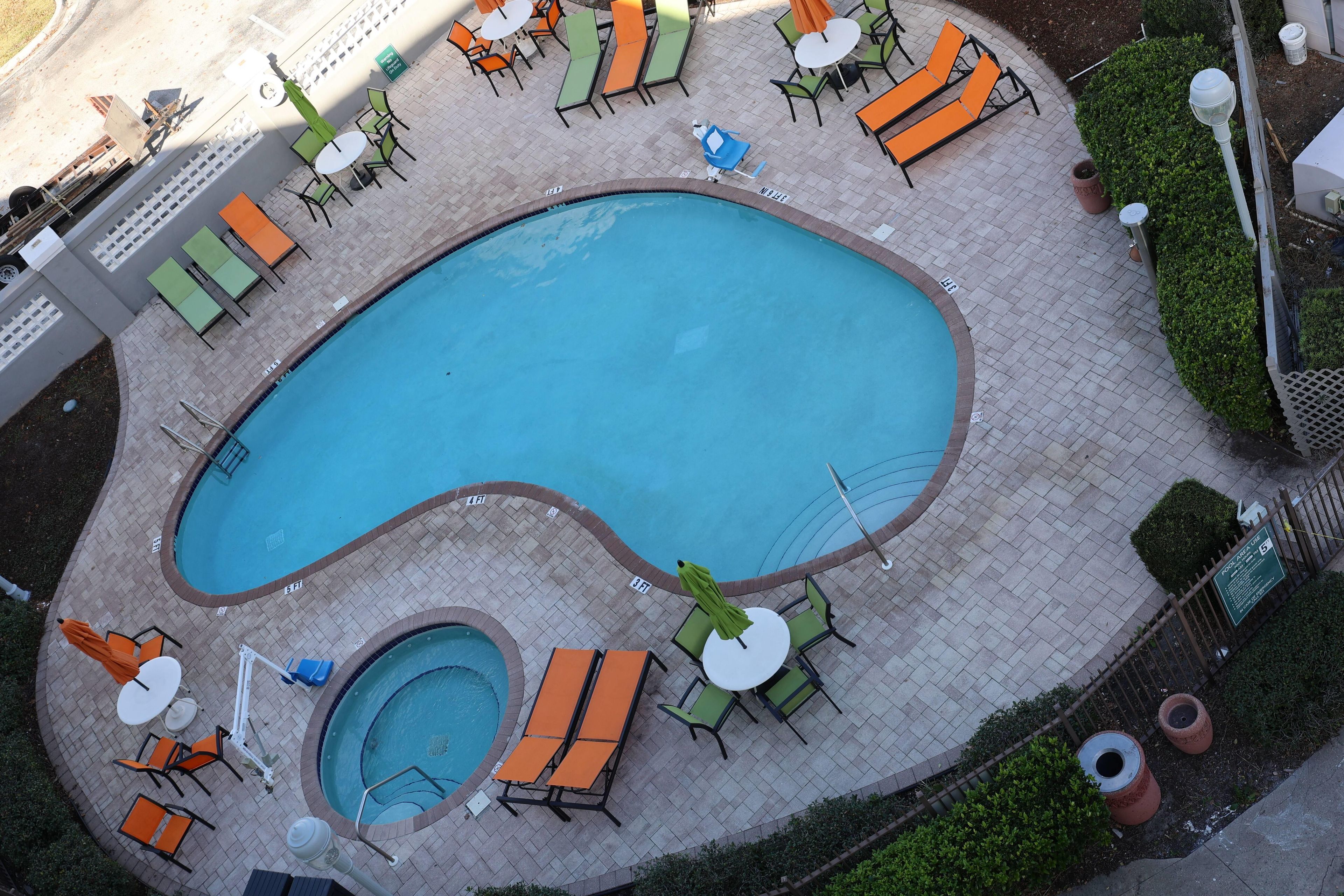 A swimming pool with lounge chairs and tables arranged around it.