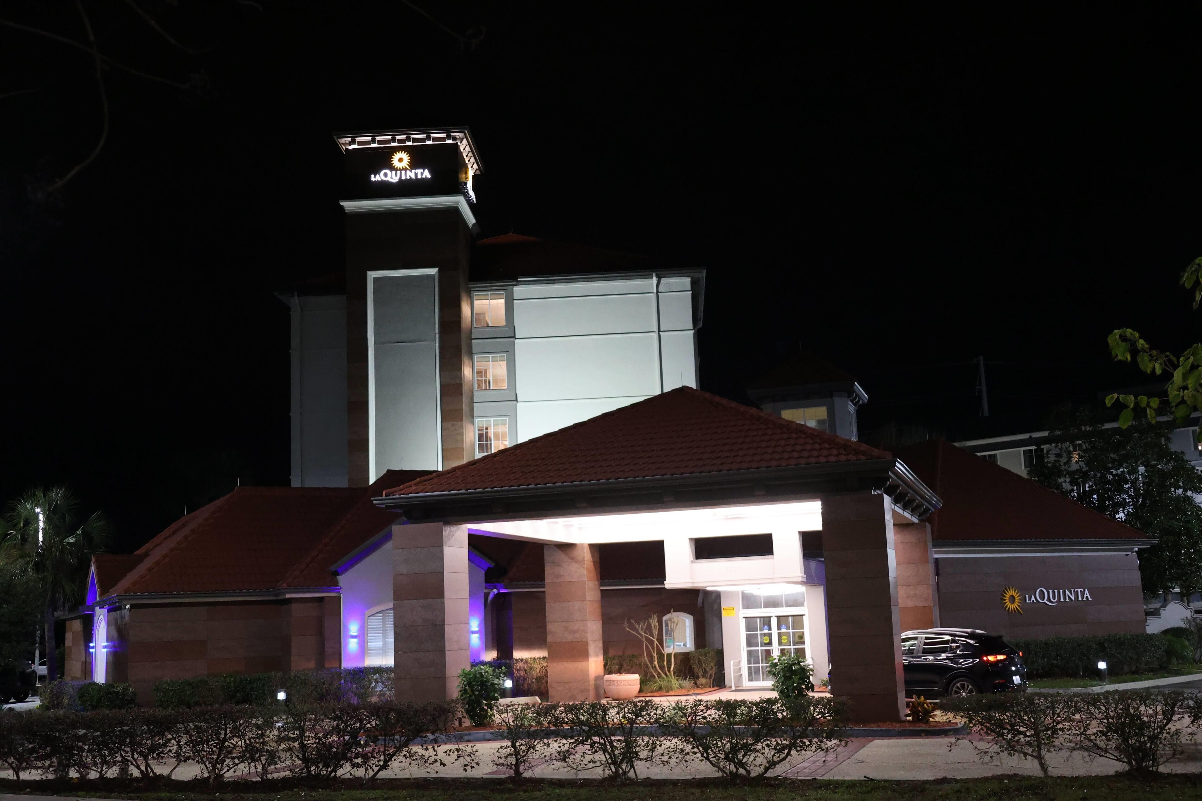 Un hotel con un letrero llamativo, un acceso cubierto y una zona de estacionamiento.