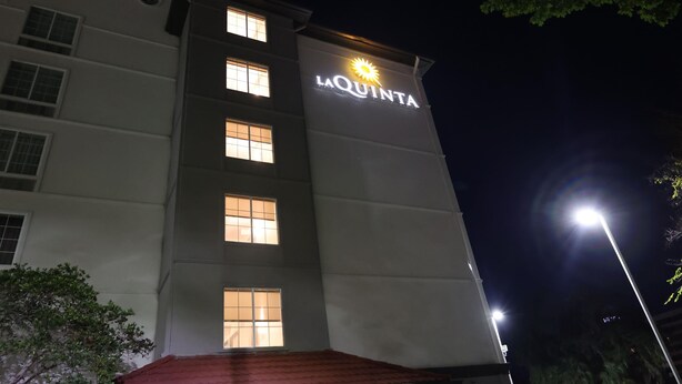 Un hotel llamado La Quinta con ventanas iluminadas y un letrero con un símbolo de sol.