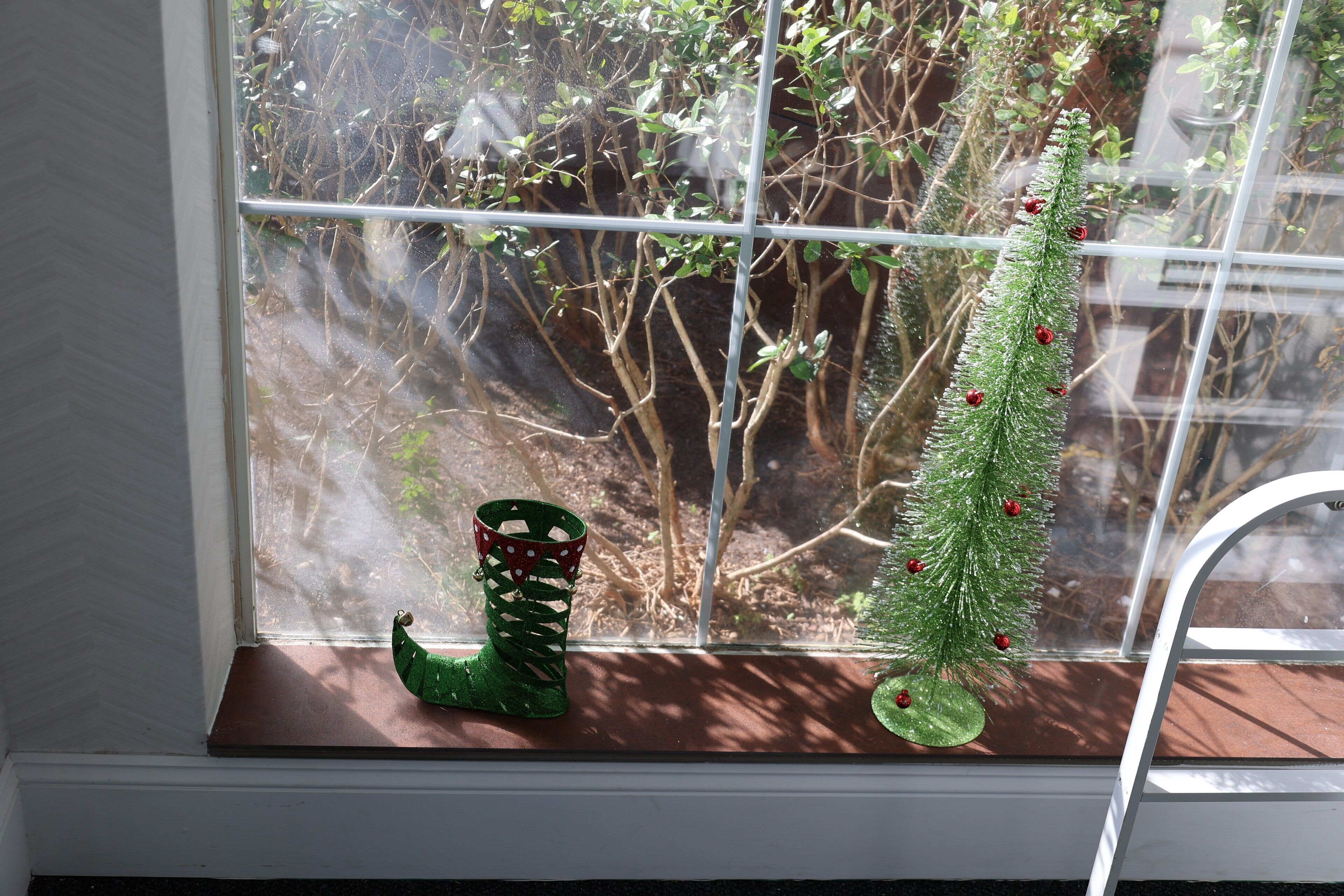 A window sill with a small Christmas tree and a decorative boot.