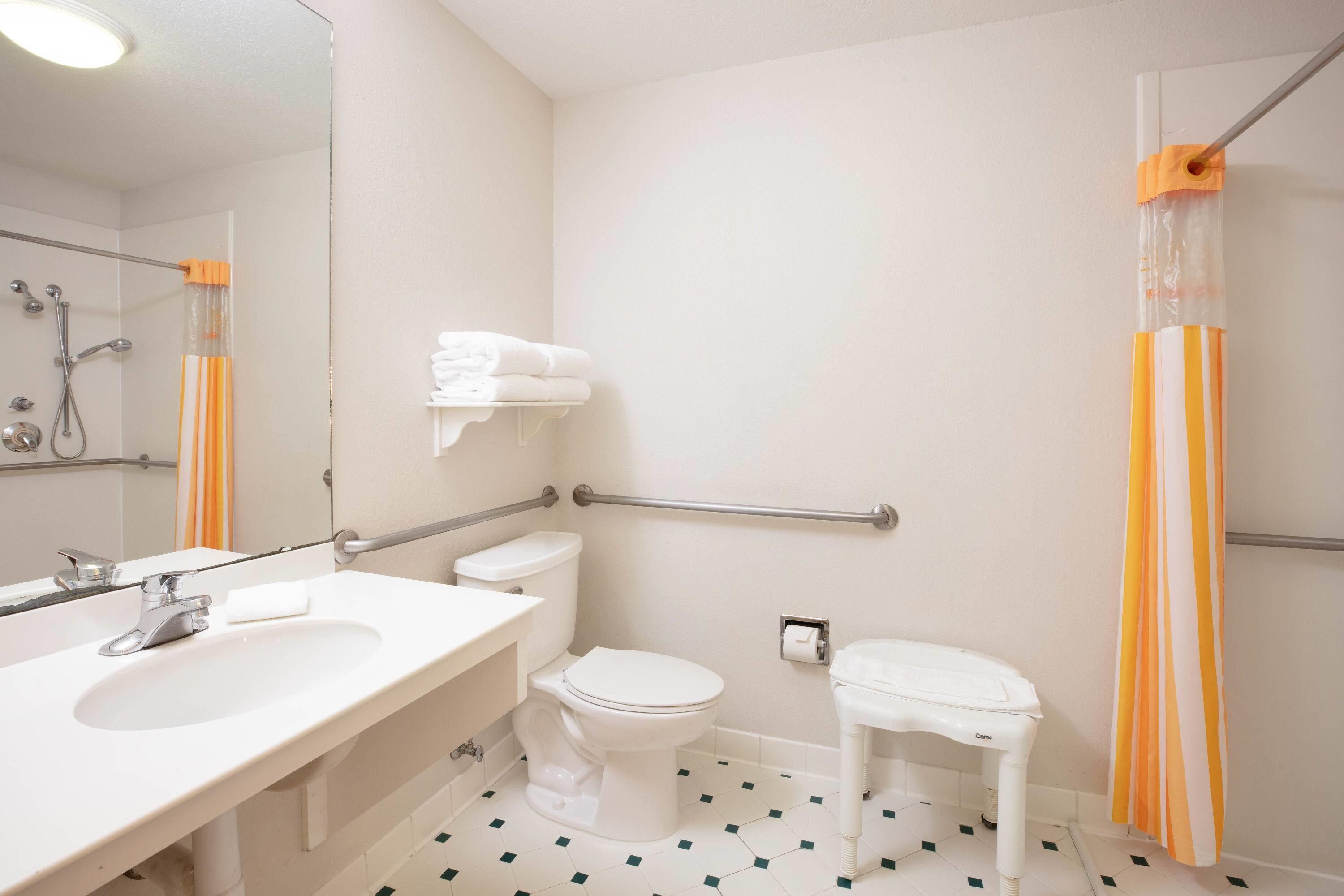 A bathroom with a white sink, toilet, and shower area.
