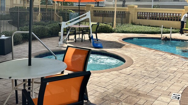 Un área de piscina con jacuzzi, sillones de descanso y una mesa.