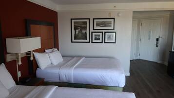 A hotel room with two beds, a nightstand, a lamp, and framed artwork on the wall.