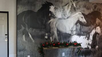 A large black and white horse mural on a wall with a small table decorated with red ornaments in front of it.