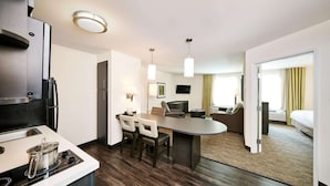 Ein modernes Hotelzimmer mit Küchenzeile, Essbereich und Schlafbereich.