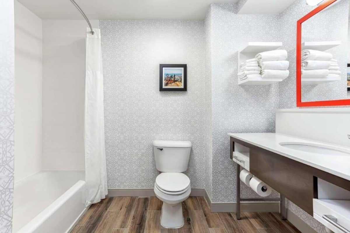 A bathroom with a toilet, shower, and sink.