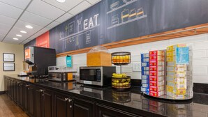 A kitchen area with a microwave, toaster, and a display of packaged food items.