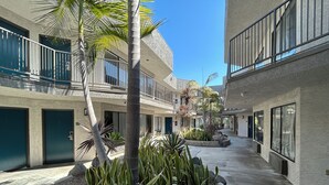 A courtyard with a central planter, multiple balconies, and a clear sky. - Studio 6 Suites Gardena, CA (Gardena)