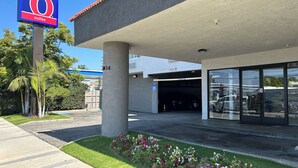 A 6-suite hotel with a large sign, a covered parking area, and a building entrance. - Studio 6 Suites Gardena, CA (Gardena)