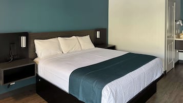 A modern hotel room with a large bed, bedside tables, a desk, and a wardrobe.