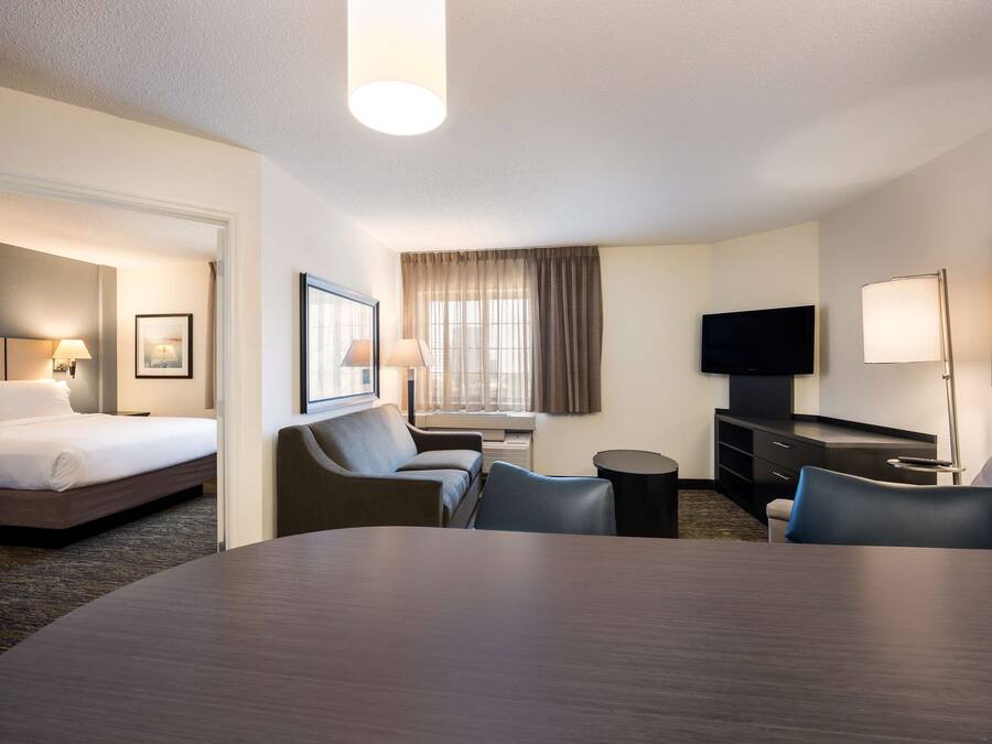 Een hotelkamer met een bed, een bureau, twee stoelen, een televisie en een lamp.