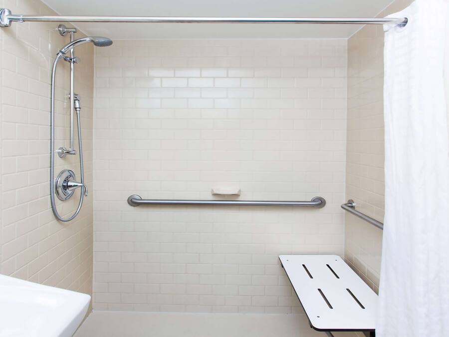 Une salle de bain équipée d’une douche, de toilettes et d’une barre d’appui.