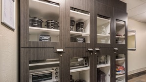 Un mueble de cocina con varios estantes que contiene electrodomésticos y recipientes de almacenamiento.