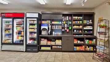 A self-service beverage station with Coca-Cola and other drinks, a coffee machine, and a variety of snacks and groceries.