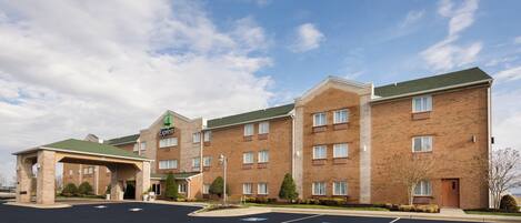 Un hotel Holiday Inn Express con facciata in mattoni, diverse finestre e un'area di parcheggio coperta.