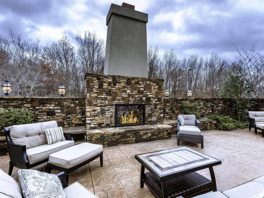 Une terrasse extérieure avec des murs en pierre, une cheminée et du mobilier d’extérieur.
