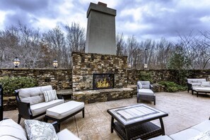 Un patio exterior con paredes de piedra, chimenea y mobiliario de exterior.