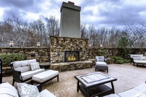 An outdoor patio with stone walls, a fireplace, and outdoor furniture.