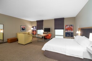 A hotel room with a large bed, a desk with a computer, a chair, and a sofa. - Hampton Inn Madison Huntsville Airport (Madison)